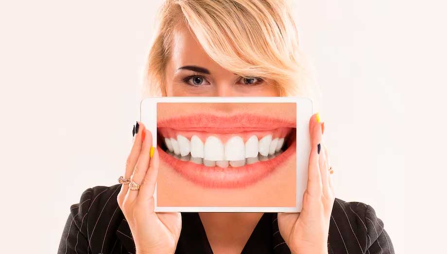 Mujer mostrando un zoom a su sonrisa a través de una tableta digital