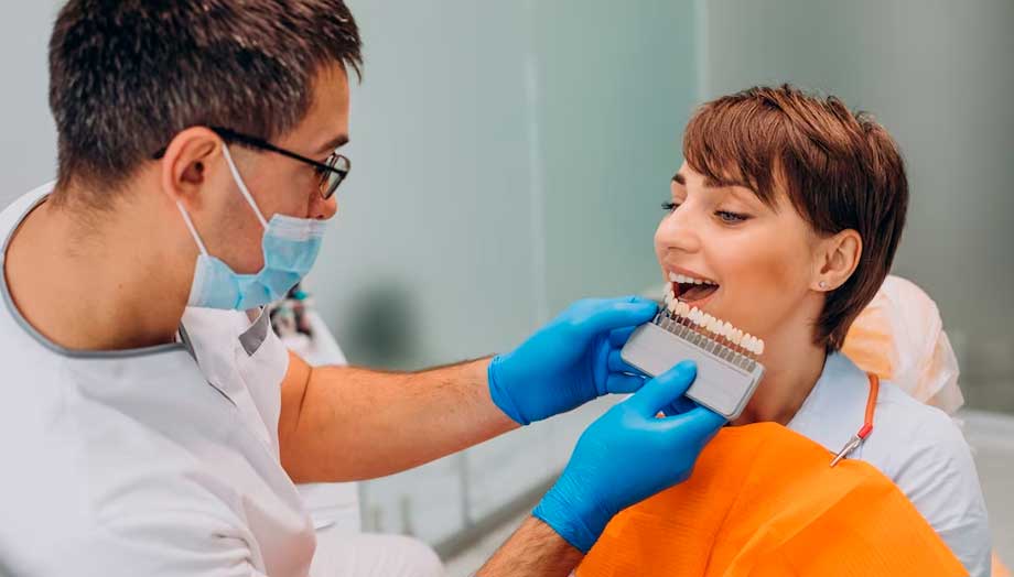 Imagen de un dentista realizando una prueba de carillas de porcelana con una paciente